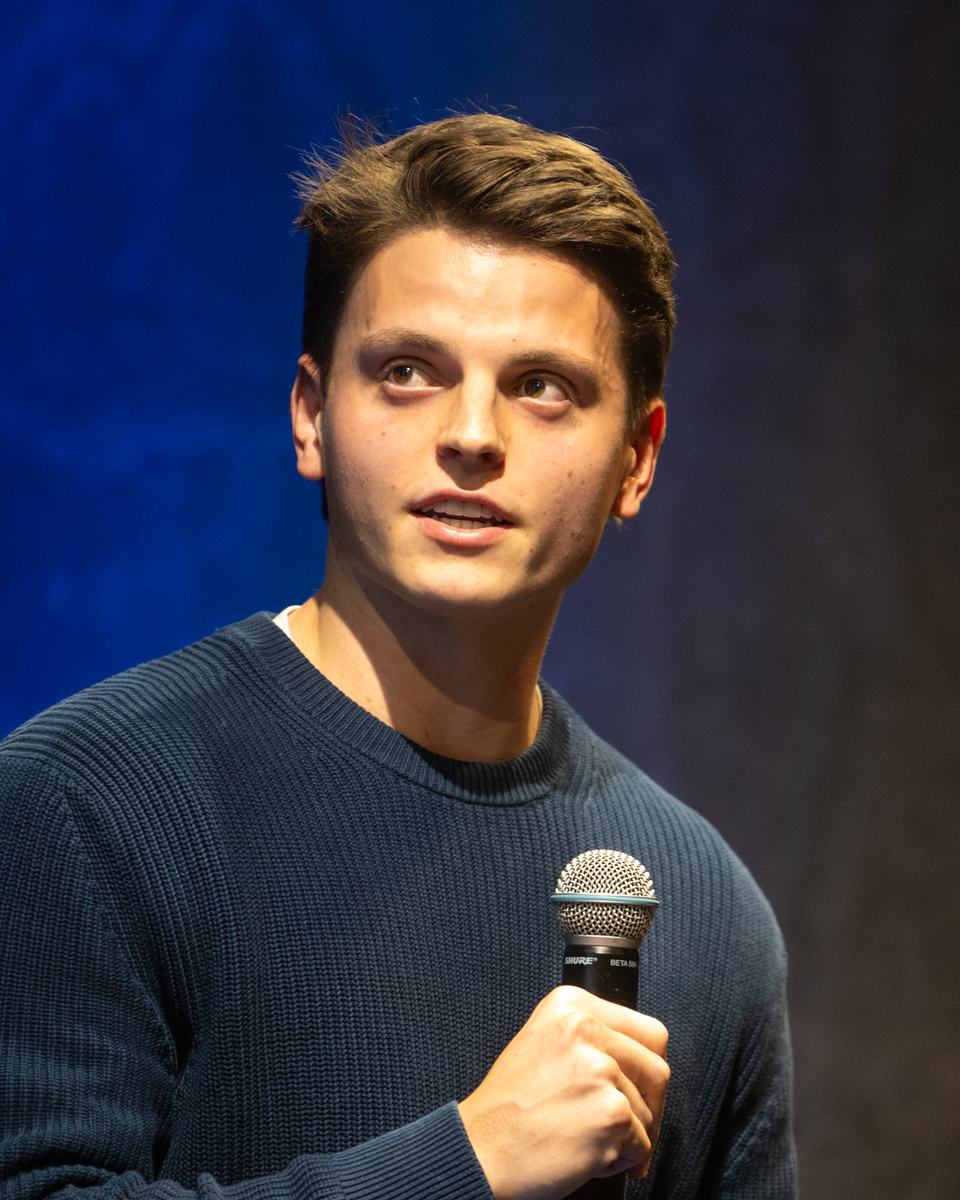 Tom van der Linden on stage, speaking into a microphone